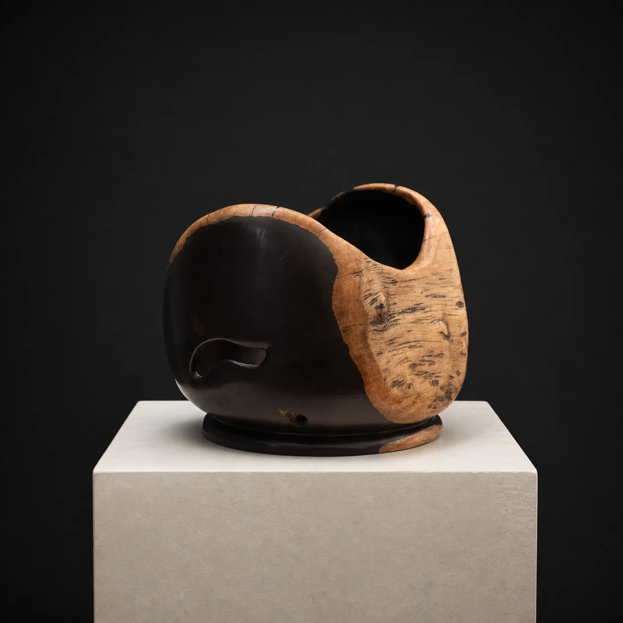 Medium Natural-Edged African Blackwood Bowl, a one-of-one African Blackwood sculpture by Rodney Band, centred on a warm limestone plinth against a charcoal studio ground.