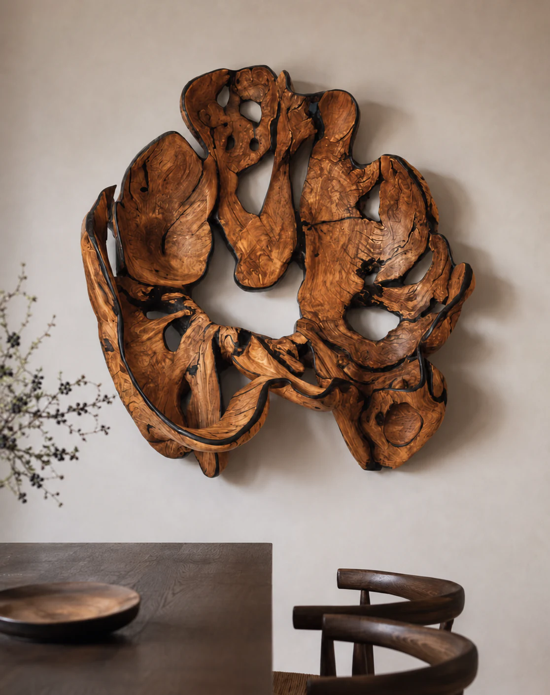 Large root wood sculpture installed on an uninterrupted pale wall above a dining table.